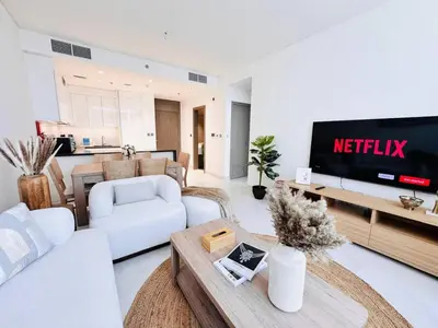 a living room with a television and white furniture at Fully Furnished 1br W Relaxing Lagoon View in Dubai