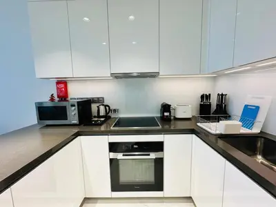 a kitchen with white cabinets and a sink and a microwave at Fully Furnished 1br W Relaxing Lagoon View in Dubai