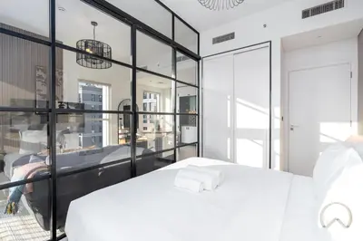 a bedroom with a white bed and glass walls at Oraya - Stylish 2BR in Socio Tower 2 With Pool View in Dubai