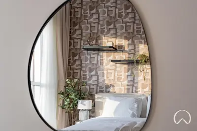 a mirror on a wall with a bed in a room at Oraya - Stylish 2BR in Socio Tower 2 With Pool View in Dubai