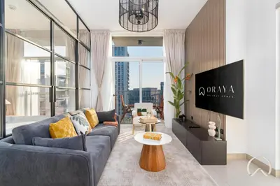 a living room with a couch and a table at Oraya - Stylish 2BR in Socio Tower 2 With Pool View in Dubai