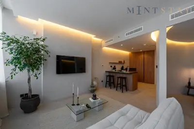 a living room with a white couch and a tv on a wall at Sky Gardens, Park Avenue, DIFC - Mint Stay in Dubai