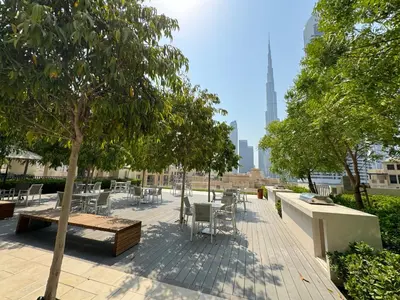 a patio with tables and chairs and a tree at Burj Royale Condo, Close to Dubai Mall & Attractions in Dubai