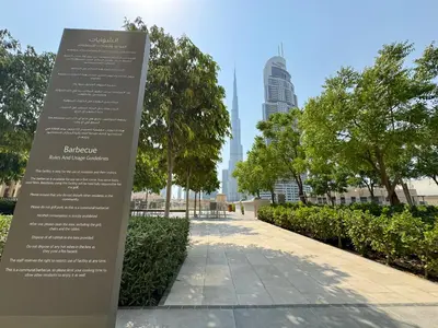 a sign in a park with buildings in the background at Burj Royale Condo, Close to Dubai Mall & Attractions in Dubai