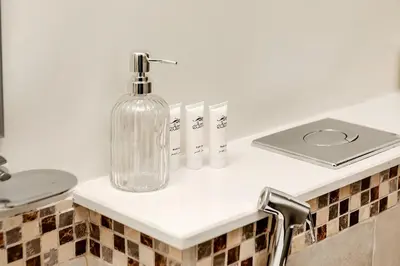 a glass bottle sitting on a counter in a bathroom at DAMAC Vera 1BR with Downtown & Burj Khalifa View in Dubai