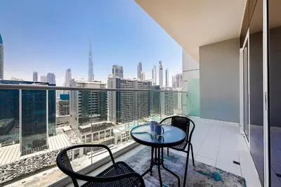 a balcony with a table and chairs and a view of the city at DAMAC Vera 1BR with Downtown & Burj Khalifa View in Dubai