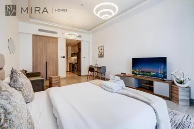 a bedroom with a large white bed and a flat screen tv at Mira Holiday Homes - Fully Furnished Studio in JLT in Dubai