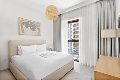 a white bedroom with a bed and a window at Silkhaus Chic 1BDR In Unique Neighborhood in Dubai