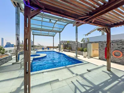 an overhead view of a swimming pool under a pergola at 1BR Apartment minutes from Mall of the Emirates in Dubai