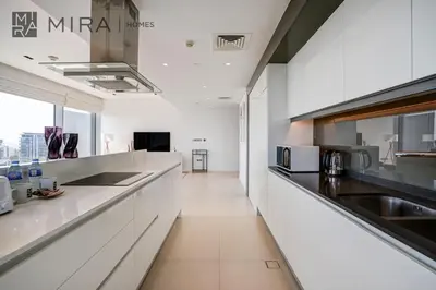 a large kitchen with white counters and a sink at Mira Holiday Homes - Lovely 3 bedroom in Bluewaters with sea view in Dubai