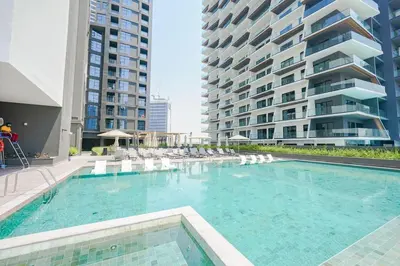 a large swimming pool with chairs and buildings at Waves - Comfort and Style in a 21st-Floor Studio With View in Dubai