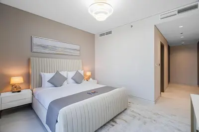 a white bedroom with a large white bed with pillows at Your Keys Holiday Homes in Dubai
