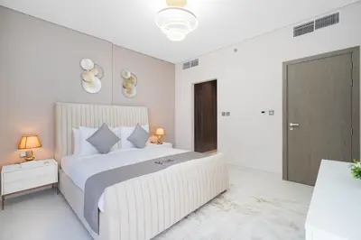 a white bedroom with a large bed with white pillows at Your Keys Holiday Homes in Dubai