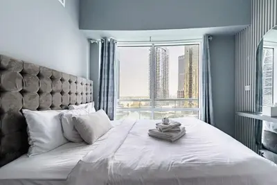a bedroom with a large bed with a large window at Stunning skyline- lake view modern cozy apartment in Dubai