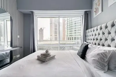 a bedroom with a white bed with a large window at Stunning skyline- lake view modern cozy apartment in Dubai