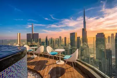 a balcony with chairs and tables and a city skyline at Premium 2 BDR Burj Khalifa Infinity Pool View in Dubai
