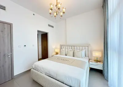 a white bedroom with a large bed and a chandelier at Extraordinary 2BR in Prive Residence, Dubai Hills in Dubai