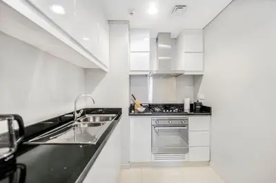 a white kitchen with a sink and a stove at Tranquil Studio with Golf View in Dubai