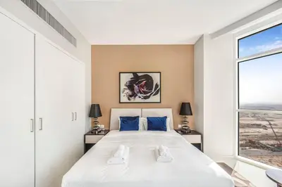 a bedroom with a large bed with blue pillows at Tranquil Studio with Golf View in Dubai