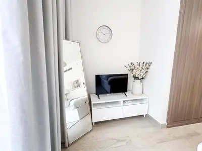 a living room with a television on a dresser with a mirror at EasyGo - Unbeatable Deals on Urban Rentals in Riviera 16 in Dubai