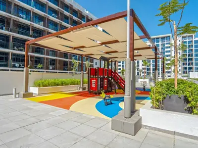 a playground in front of a large building at EasyGo - Unbeatable Deals on Urban Rentals in Riviera 16 in Dubai