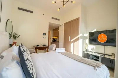 a bedroom with a large white bed and a tv at EasyGo - Unbeatable Deals on Urban Rentals in Riviera 16 in Dubai
