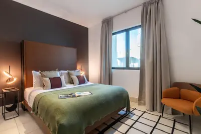 a bedroom with a bed and a chair and a window at The Smart Concierge - Reehan 6 in Dubai