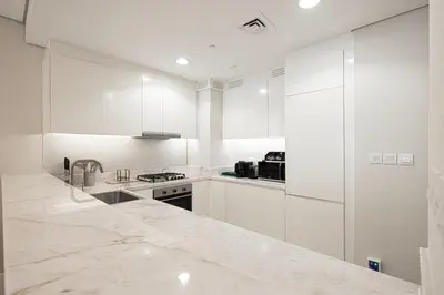 a kitchen with white cabinets and a marble counter top at Boulevard 2 Bedroom Family Apartment with BURJ KHALIFA view and INFINITY POOL in 64th Floor Dubai Downtown in Dubai