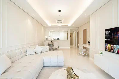 a white living room with a large white couch at Boulevard 2 Bedroom Family Apartment with BURJ KHALIFA view and INFINITY POOL in 64th Floor Dubai Downtown in Dubai