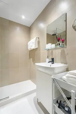 a white bathroom with a sink and a shower at Bright Downtown Dubai Studio by Mall, Burj Khalifa & Fountains in Dubai