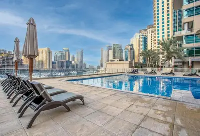 a pool with chairs and an umbrella and buildings at Stylish Upgraded 1 Bedroom Marina Escape in Dubai