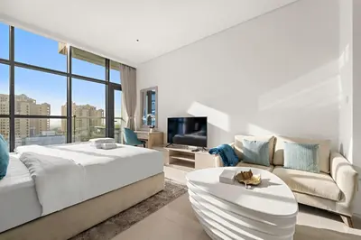 a white bedroom with a large bed and a couch at Stonetree - Brand New Studio - Prime Location in Dubai