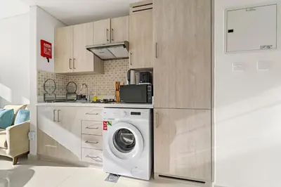 a kitchen with a washing machine and a microwave at Stonetree - Brand New Studio - Prime Location in Dubai