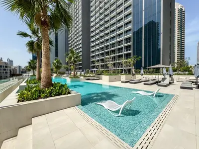 an infinity pool with two chairs and palm trees in a building at High Floor Burj Khalifa View 1BR - Business Bay in Dubai