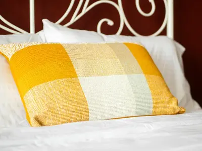 a yellow pillow sitting on a bed with white sheets at Spacious 2BR in Downtown in High Floor in Dubai