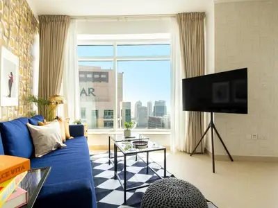 a living room with a blue couch and a large window at Spacious 2BR in Downtown in High Floor in Dubai
