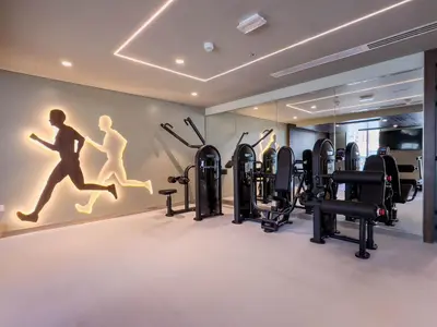 a gym with cardio equipment and a wall with a mural at Globalstay Creek Horizon Modern Apartments in Dubai