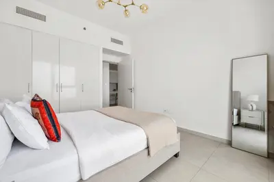 a white bedroom with a bed and a mirror at 1BR with Park & Downtown Views plus Dubai Frame in Dubai