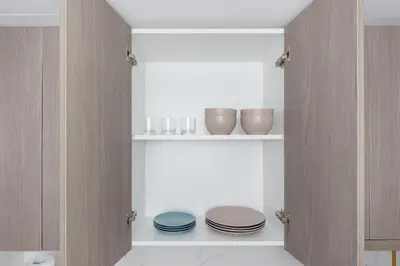 a pantry with plates and bowls on shelves at Shining studio in Laya Heights in Dubai