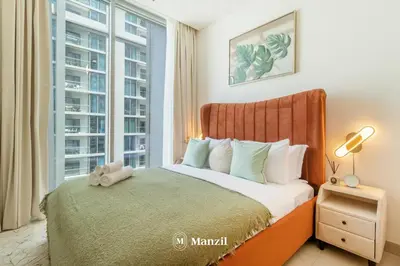 a bedroom with a bed and a large window at Manzil - 1BR Apartment in Sobha Hartland with City Views in Dubai