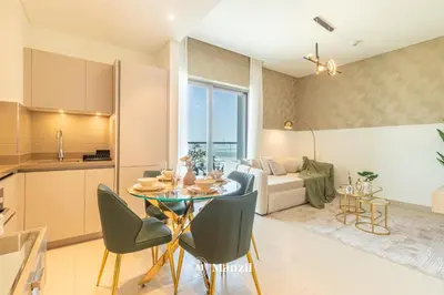 a kitchen and living room with a table and chairs at Manzil - 1BR Apartment in Sobha Hartland with City Views in Dubai