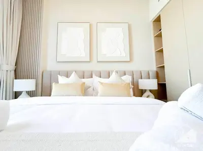 a white bedroom with two beds and two pictures on the wall at Amazing stay at Dubai creek with Balcony & View in Dubai