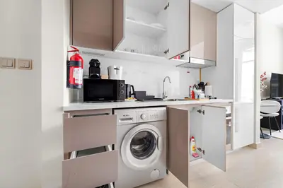a white kitchen with a washing machine in it at Silkhaus Luxurious Studio in High End Neighborhood in Dubai