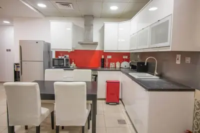 a kitchen with white cabinets and a red wall at Ideal for Families Close to ALL Amenities in Dubai