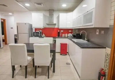 a kitchen with white cabinets and a red refrigerator at Ideal for Families Close to ALL Amenities in Dubai