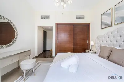 a bedroom with a large white bed and a chair at Charming 1BR Apartment in Sparkle Tower 1, Dubai Marina by Deluxe Holiday Homes in Dubai