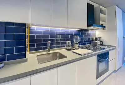 a kitchen with white cabinets and blue tiles at City Retreat MAG 318,Downtown Dubai 5 minutes walk to Dubai mall in Dubai
