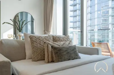 a living room with a couch and a large window at Oraya - Sleek 1BR In District one , Direct Lagoon Access in Dubai