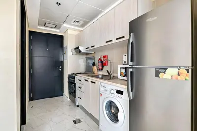 a kitchen with a refrigerator and a washing machine at Chic Urban Escape at Studio MAG 422 in Dubai