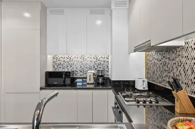 a kitchen with white cabinets and a stove top oven at Luxury Stay with Burj Khalifa Views & Infinity Pool in Dubai